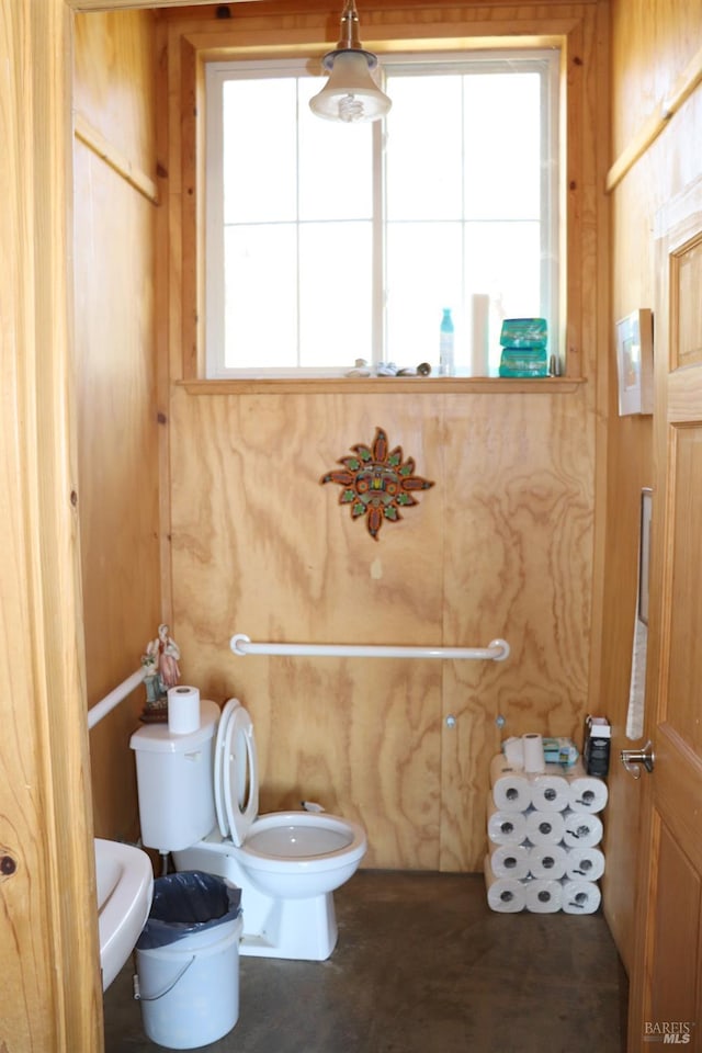 bathroom with toilet, a bidet, and wooden walls