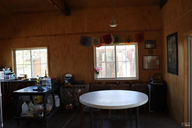 dining room with wooden walls and beamed ceiling