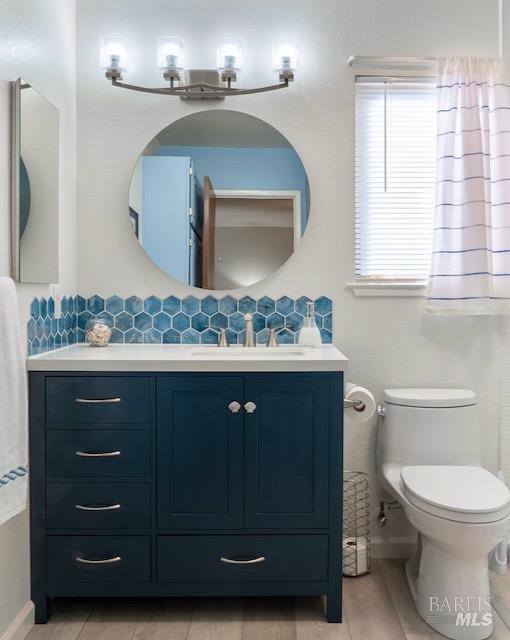 bathroom featuring wood-type flooring, vanity, tasteful backsplash, and toilet