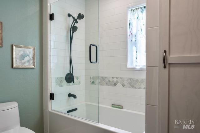 bathroom with combined bath / shower with glass door and toilet