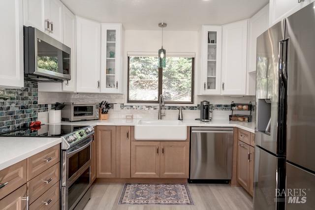 kitchen featuring glass insert cabinets, a sink, backsplash, and appliances with stainless steel finishes