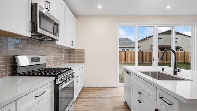 kitchen featuring light stone countertops, white cabinetry, appliances with stainless steel finishes, and sink