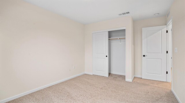 unfurnished bedroom featuring light colored carpet and a closet