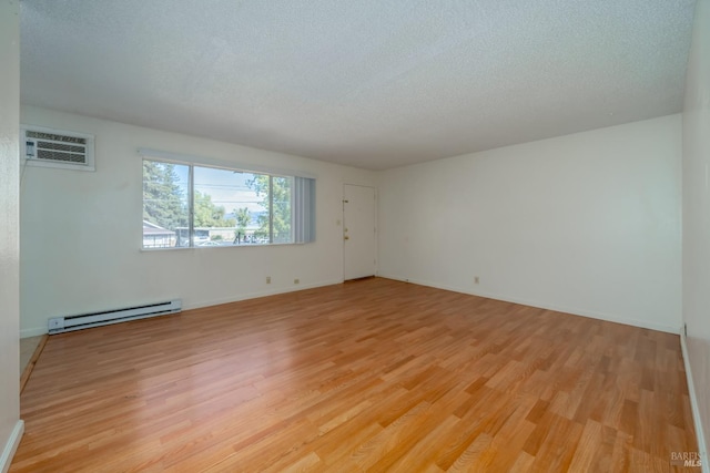 15 Royale Ave, Lakeport, CA 95453 - unfurnished room with a wall unit AC, a baseboard heating unit, light hardwood / wood-style floors, and a textured ceiling