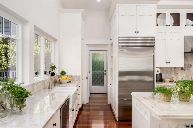 kitchen featuring light stone counters, dark wood-type flooring, stainless steel built in refrigerator, white cabinetry, and black dishwasher