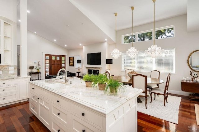 kitchen featuring an island with sink, sink, an inviting chandelier, and dark hardwood / wood-style flooring