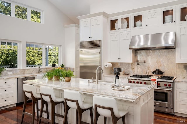 kitchen with wall chimney exhaust hood, plenty of natural light, high end appliances, and sink