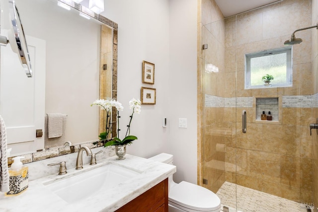 bathroom featuring a shower with shower door, vanity, and toilet