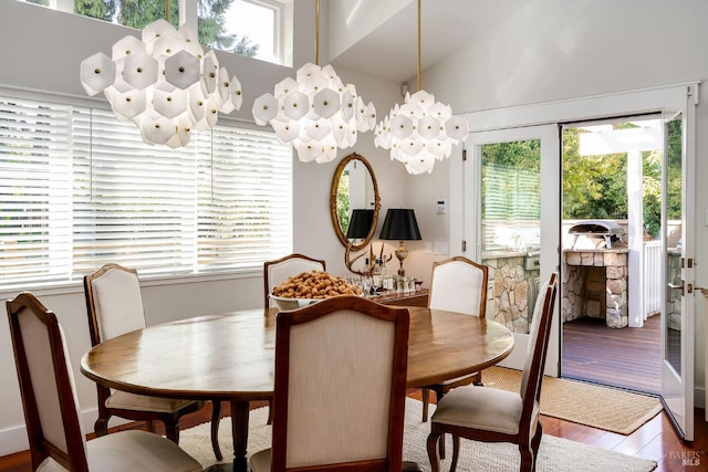 dining room with wood-type flooring, vaulted ceiling, a chandelier, and a wealth of natural light