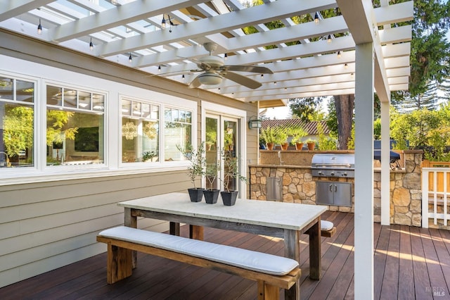 wooden deck with an outdoor kitchen, area for grilling, a pergola, and ceiling fan