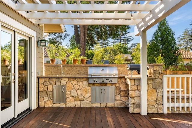 deck with an outdoor kitchen, area for grilling, and a pergola