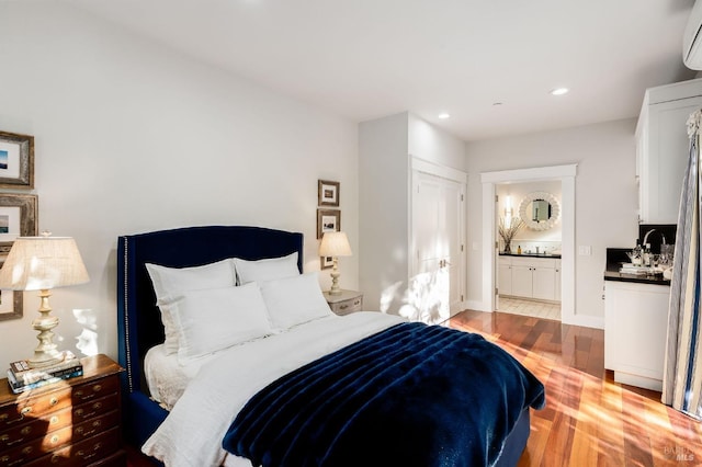 bedroom featuring ensuite bathroom, sink, and light hardwood / wood-style floors