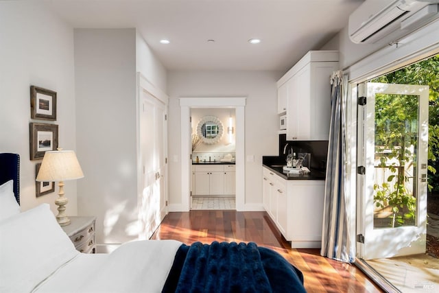 interior space with sink, ensuite bath, dark wood-type flooring, and an AC wall unit