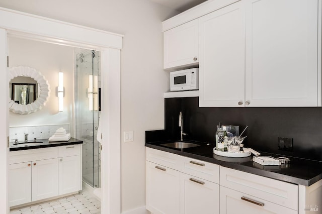 kitchen featuring backsplash, sink, and white cabinetry