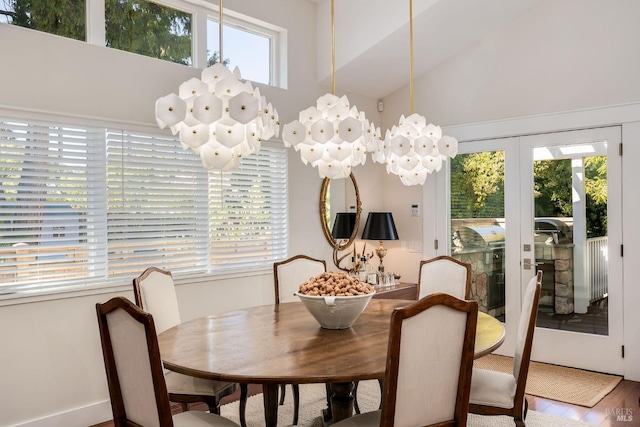 dining space featuring high vaulted ceiling, a notable chandelier, a wealth of natural light, and hardwood / wood-style floors