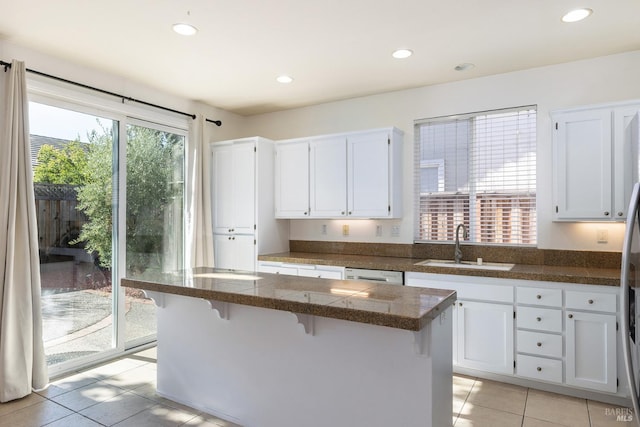 kitchen with dishwasher, white cabinetry, sink, and a breakfast bar