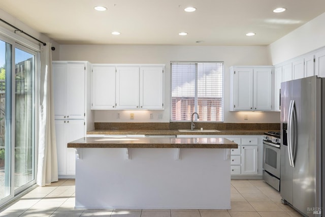 kitchen featuring a breakfast bar, sink, a kitchen island, stainless steel appliances, and white cabinets