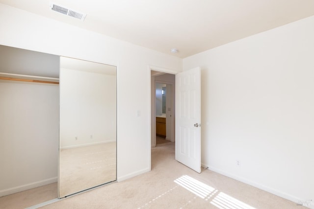 unfurnished bedroom featuring light colored carpet and a closet