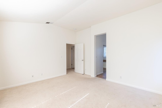 empty room featuring vaulted ceiling and light colored carpet