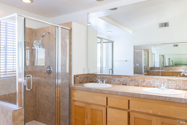 bathroom featuring a shower with door, vanity, lofted ceiling, and backsplash