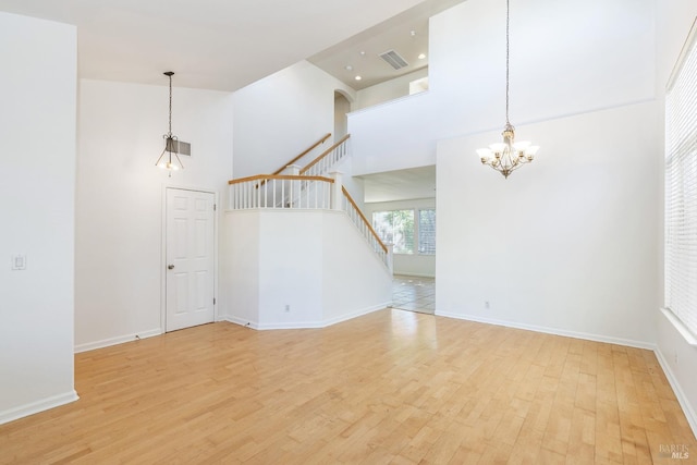 empty room featuring a notable chandelier, hardwood / wood-style floors, and a high ceiling