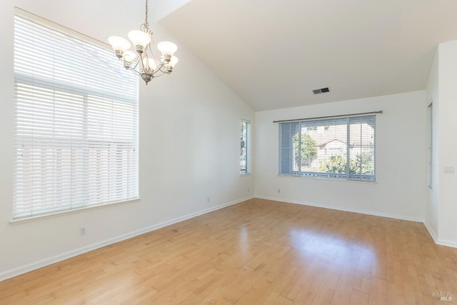 unfurnished room with lofted ceiling, a chandelier, and light hardwood / wood-style flooring