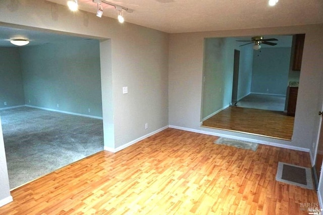 carpeted spare room featuring rail lighting and ceiling fan