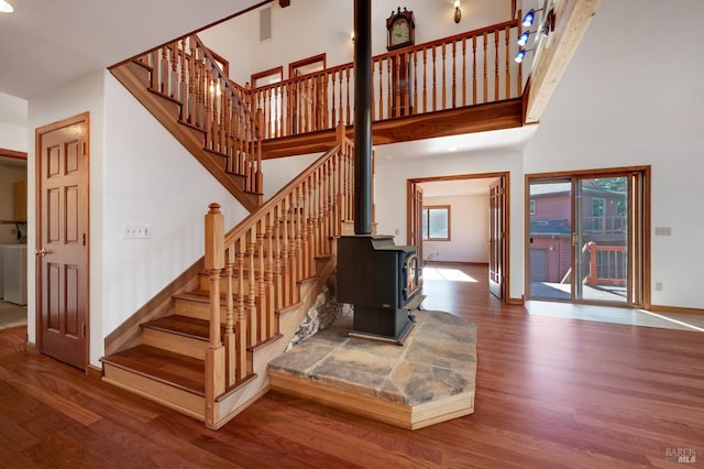 stairway with a wood stove, washer / dryer, hardwood / wood-style floors, and a high ceiling