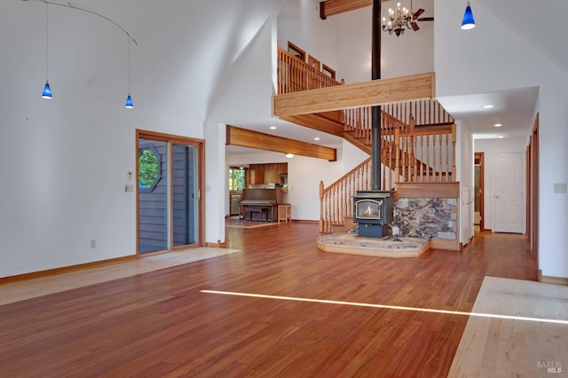 unfurnished living room with a wood stove, hardwood / wood-style flooring, and high vaulted ceiling