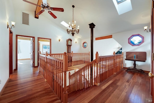 corridor with a skylight, high vaulted ceiling, dark wood-type flooring, and a chandelier