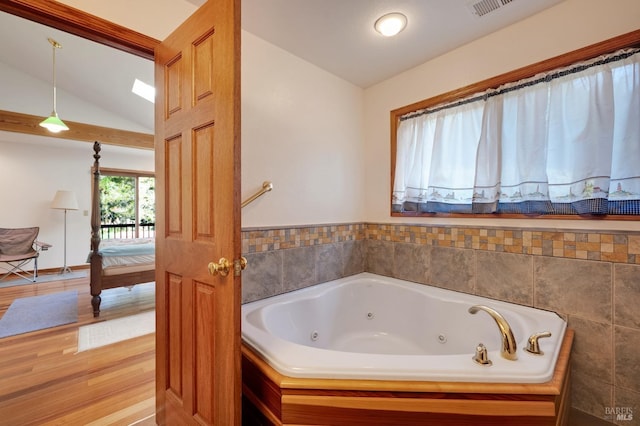 bathroom featuring a bathtub, hardwood / wood-style floors, and vaulted ceiling