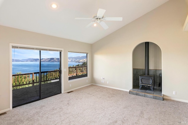 unfurnished living room with a water view, vaulted ceiling, carpet flooring, and ceiling fan