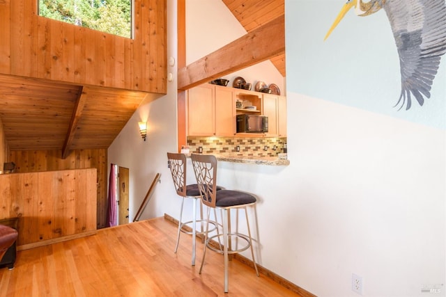 kitchen with white cabinetry, wood ceiling, vaulted ceiling with beams, light wood-type flooring, and decorative backsplash