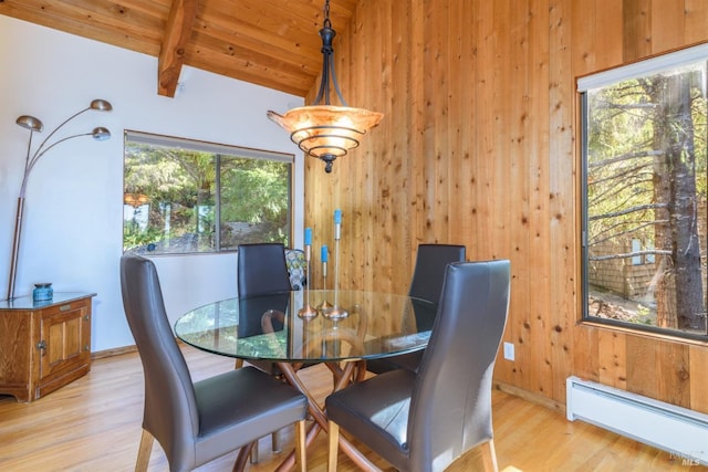 dining room featuring light hardwood / wood-style flooring, wooden walls, and a baseboard radiator