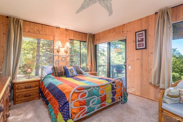 bedroom featuring multiple windows, wooden walls, and light carpet