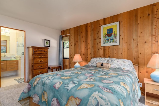 carpeted bedroom featuring connected bathroom, wood walls, and sink