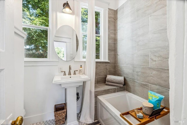 bathroom with a tub and baseboards