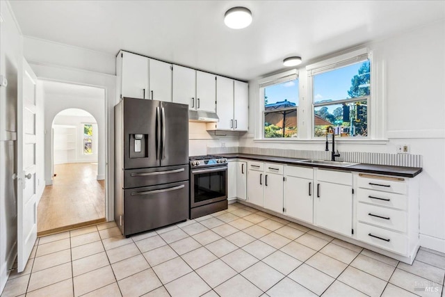 kitchen with under cabinet range hood, appliances with stainless steel finishes, dark countertops, and a sink