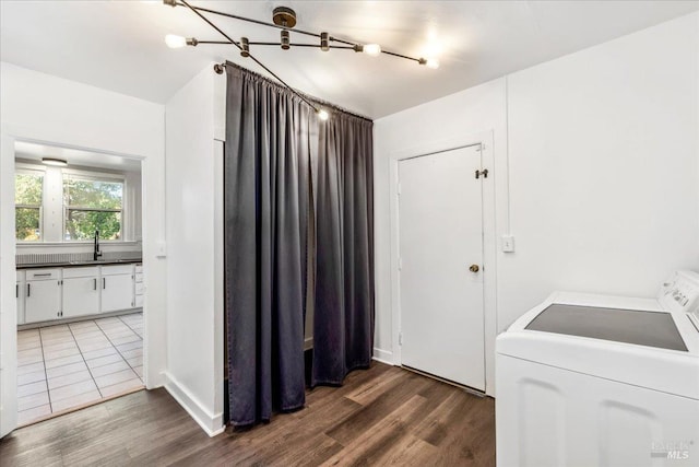 washroom with wood finished floors, washing machine and dryer, laundry area, and a sink