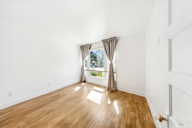 unfurnished room with baseboards and wood finished floors