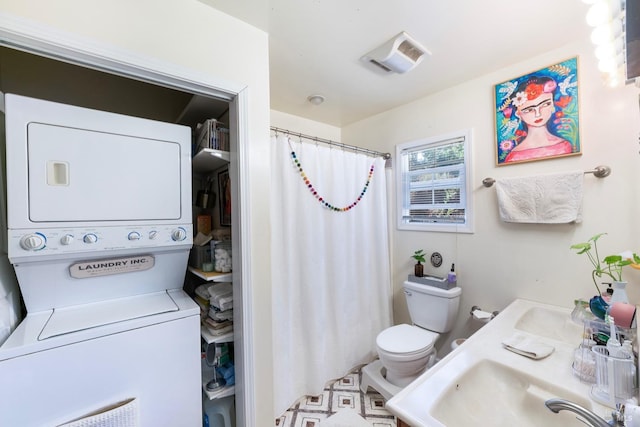 bathroom featuring stacked washer / drying machine, toilet, and sink