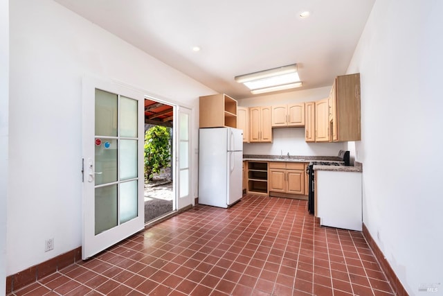 kitchen with light brown cabinetry, dark tile patterned floors, white appliances, and sink