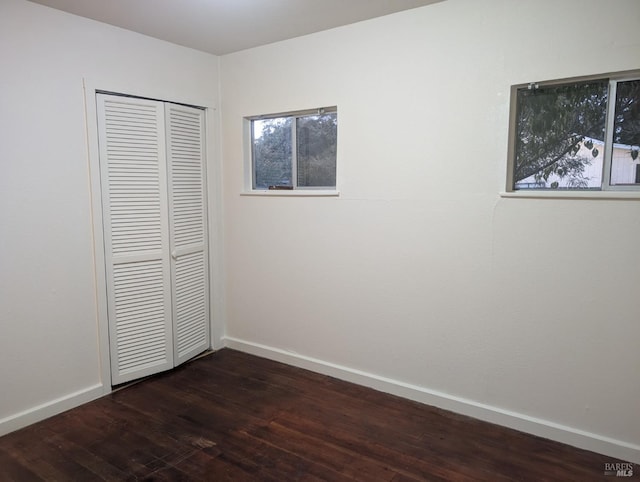 unfurnished bedroom with a closet and dark hardwood / wood-style flooring