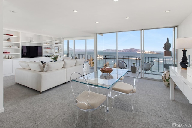 carpeted living room featuring a mountain view and a wall of windows