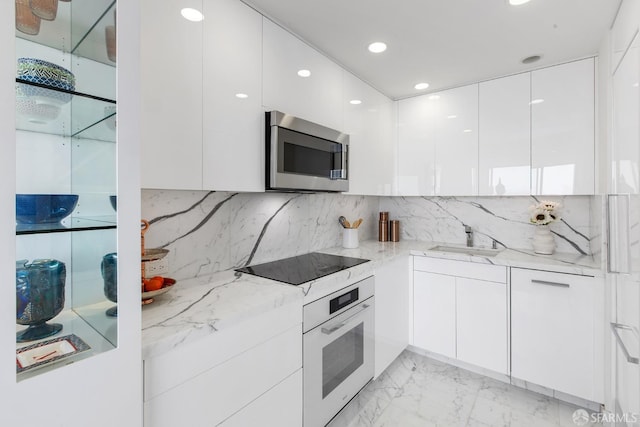 kitchen featuring sink, white oven, black electric cooktop, white cabinets, and light stone counters