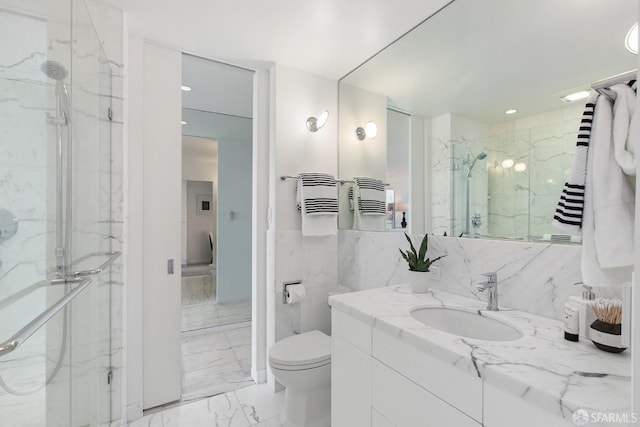 bathroom with vanity, walk in shower, toilet, and tile walls