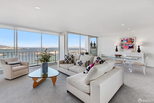 carpeted living room featuring a water view and expansive windows