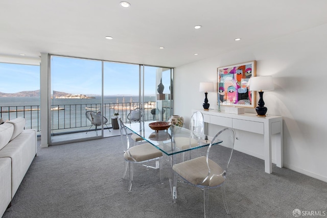 carpeted dining room featuring a water and mountain view and a wall of windows