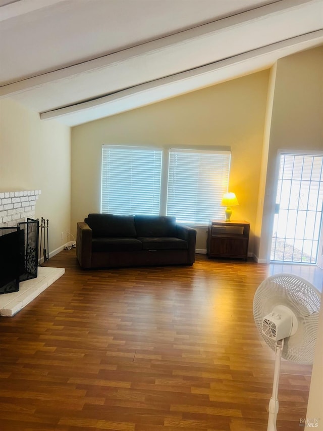 living room with vaulted ceiling with beams, hardwood / wood-style flooring, and a fireplace