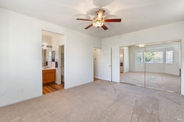 unfurnished bedroom with light carpet, ensuite bath, ceiling fan, sink, and a closet